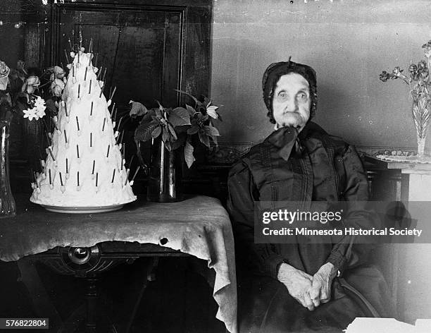 Sarah Doherty poses beside her conical cake on her 100th birthday.