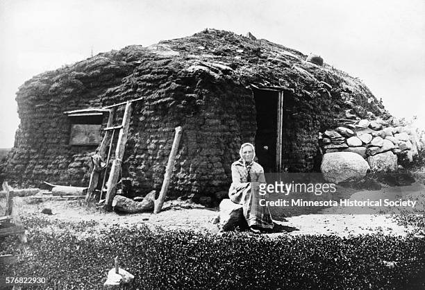 Norwegian immigrant Beret Olesdater Hagebak rests in front of her sod house in Lac Qui Parle County. | Location: East of Madison, Minnesota, USA.