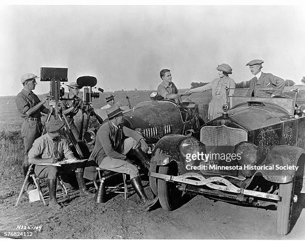 Movie crew and actors film a scene in an adaptation of Sinclair Lewis's "Free Air" in a farming field.