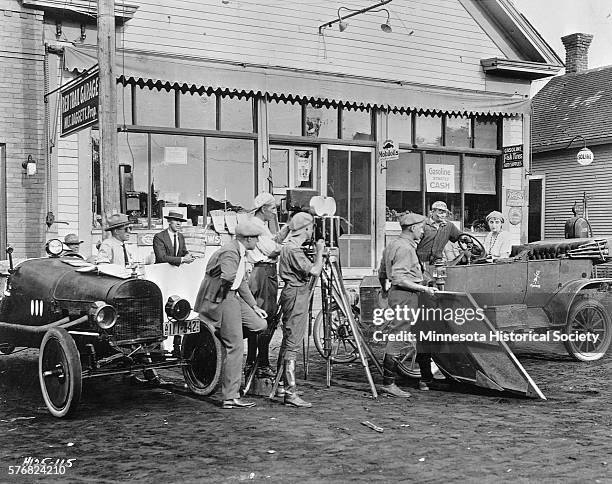 Movie crew and actors film a scene in an adaptation of Sinclair Lewis's "Free Air" in front of a general store.