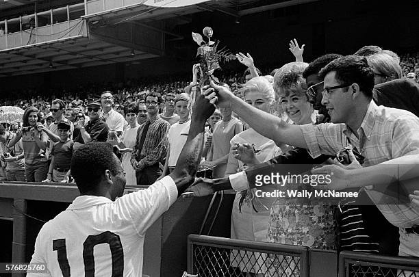 Pele, the most popular athlete in the world in his era, declared a "National Treasure" by Brazil, greets fans and receives flowers from them after a...