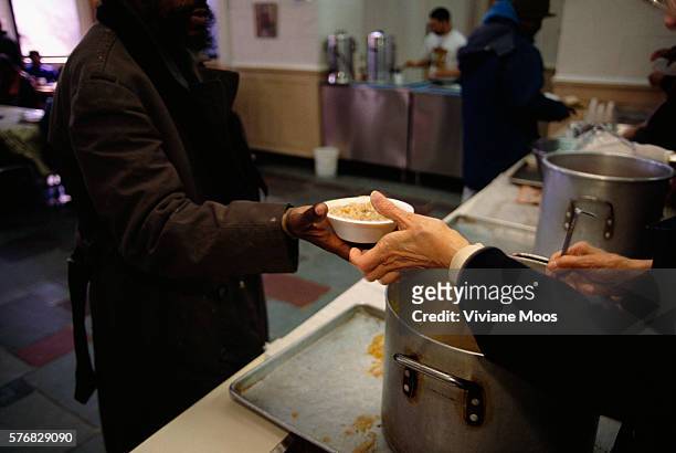 Homeless man receives a bowl of hot soup from a volunteer at the St. John's Bread and Life soup kitchen.