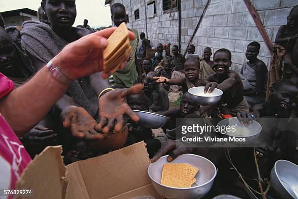Volunteer distributes crackers to refugees at a feeding center in Kongor, Sudan.