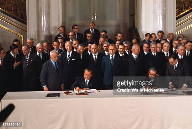 At a summit meeting in Moscow ca. May 1972, American President Richard Nixon joins in the signing of a treaty with Soviet leader Leonid Brezhnev ....
