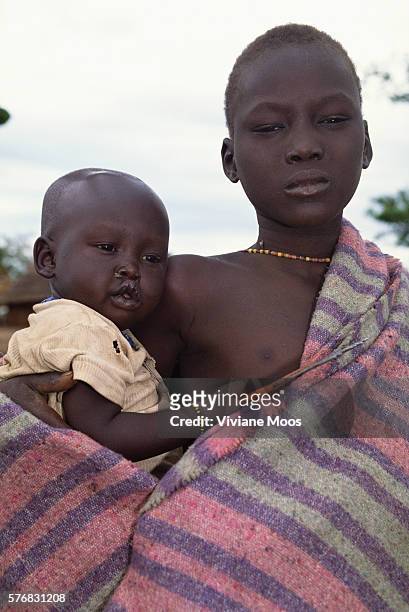 Boy holds his infant brother in the refugee camp of Ame, Sudan. Civil war and widespread famine have ravaged Sudan for decades, resulting in more...