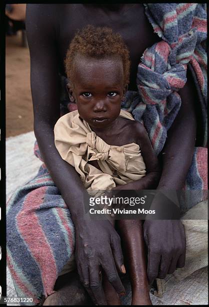 Refugee child awaits a meal at the feeding center in Ame, Sudan. Civil war and widespread famine have ravaged Sudan for decades, resulting in more...