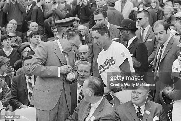 President Richard Nixon autographs a baseball for a Washington Senators team member as baseball commissioner Bowie Kuhn turns to watch. Washington...