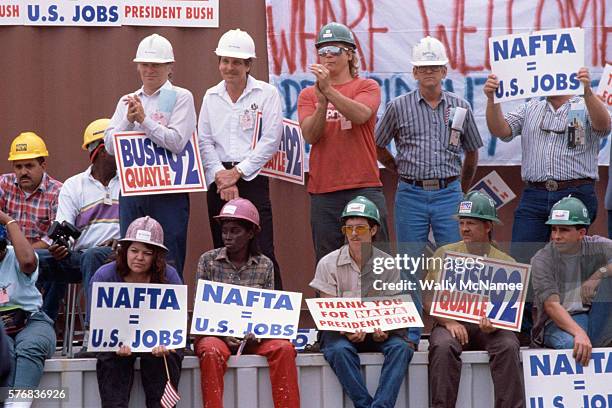 Men and women hold signs supporting NAFTA and George Bush at a rally.
