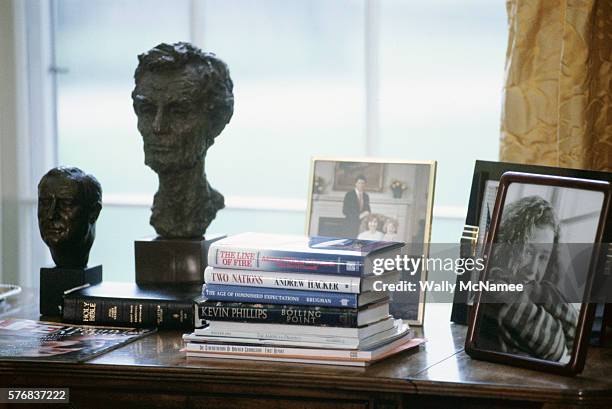 Books, family portraits, the Bible, and portrait sculptures of past presidents are some of the items on President Clinton's desk in the Oval Office .