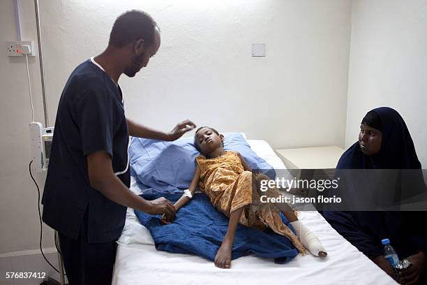 Young girl is treated inside Villa Somalia Clinic for an injured foot as her mother looks on. March 2011