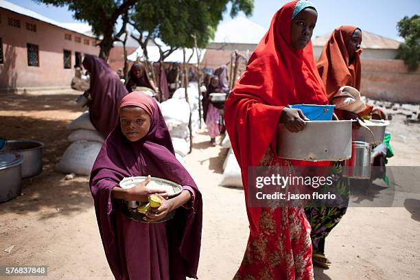 Young Somali girl and mother gathers free food at a feeding kitchen operated by the Non Government Organization SAACID. SAACID has been running a...