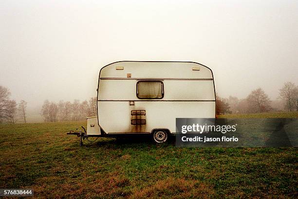 Small caravan trailer standing alone in a field on a winters day.