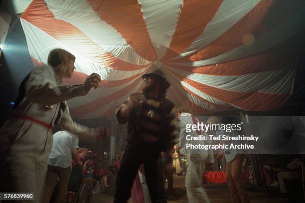 Doris Delay, dressed in a white jumpsuit, dances with a member of the Hell's Angels at the Acid Test Graduation. During this celebration, which was...