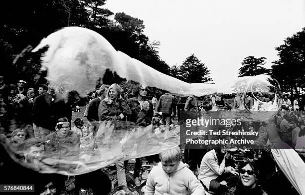 Someone in a crowd of hippies blows a giant bubble, which refracts the view of the crowd, during a love-in at San Francisco's Golden Gate Park.