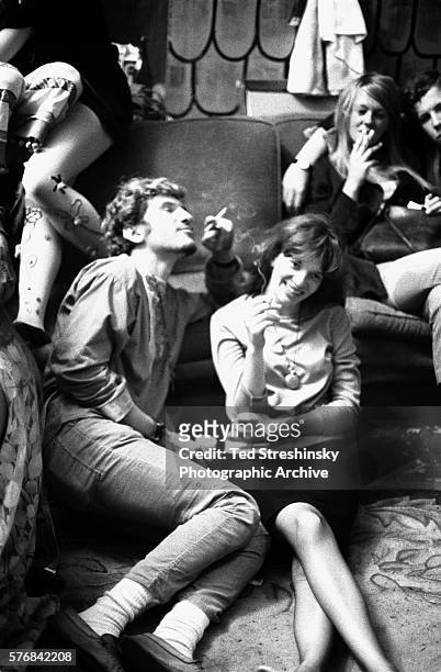 Young couple sits on the floor and smoke at the Merry Pranksters' Acid Test Graduation. They are probably high on LSD-25.