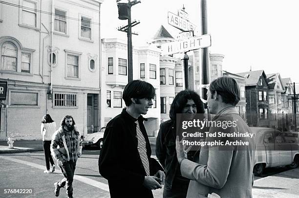 Author Tom Wolfe talks with Jerry Garcia of the Grateful Dead and the band's manager Rock Scully under the street signs on the corner of Ashbury and...
