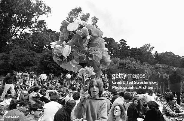 Boy carries bunch of paper flowers on a pole at a summer solstice celebration at Golden Gate Park in San Francisco.
