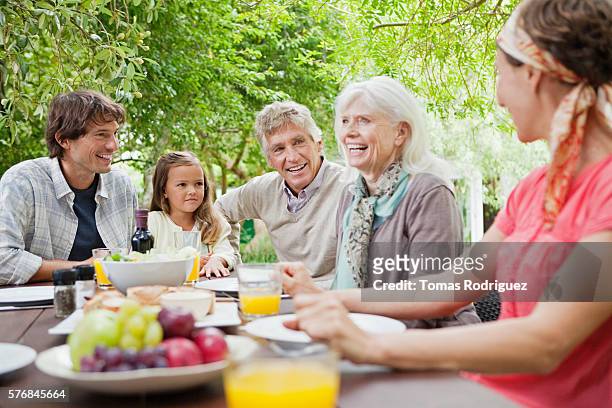 three generation family with girl (6-7 years) at garden table - 60 69 years foto e immagini stock