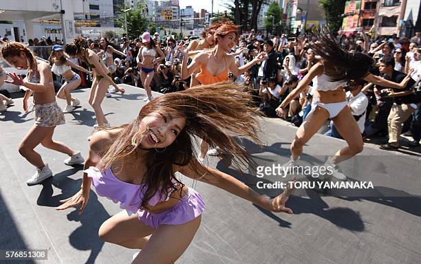 Dancers wearing new bikinis perform in front of passers-by and a line of photographers during a promotional flash mob event on a square outside...