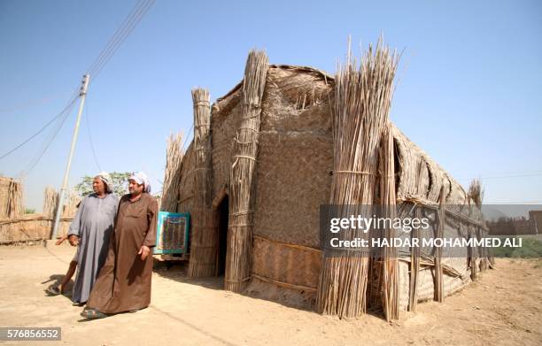 Iraqi men stand outside a hut on July 14, 2016 in the Ahwar area in the southern Maysan province -- also known as the Iraqi Marshlands -- one of the...