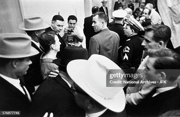Lee Harvey Oswald being led through Dallas Police Headquarters shortly before he was shot by Jack Ruby.