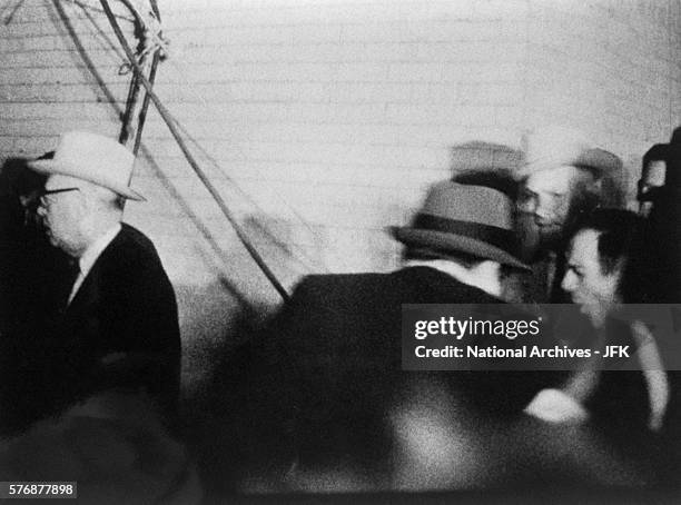 Camera captures the back of Jack Ruby as he shoots Lee Harvey Oswald who is being escorted by guards during a television press conference at the...