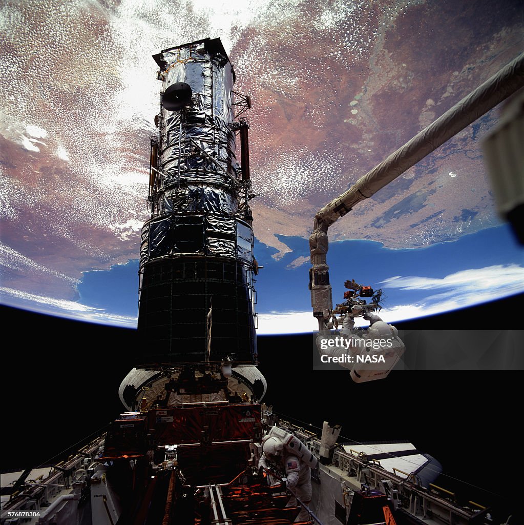 Earth over Astronauts Repairing Hubble Telescope