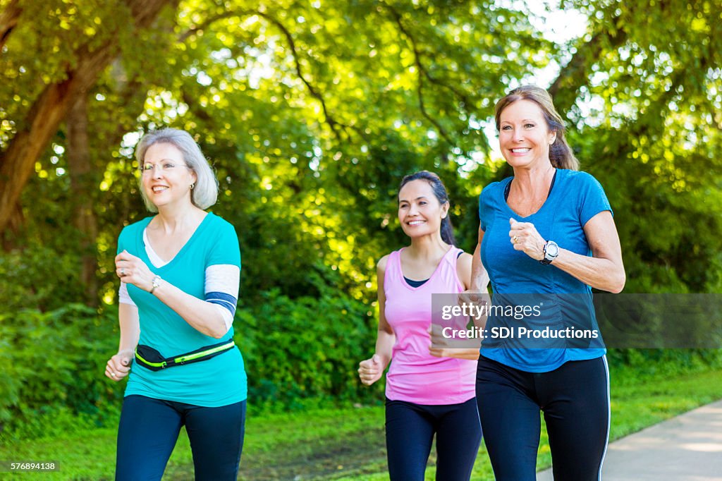 Diverse senior female friends jog on sunny day