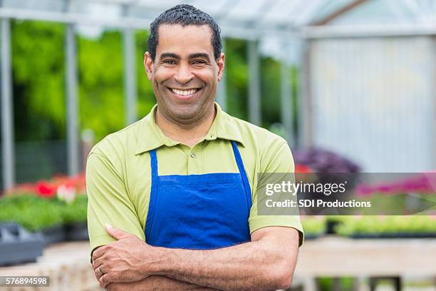 confident african american garden center owner in greenhouse - avental imagens e fotografias de stock