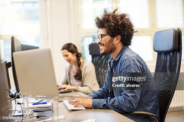 glückliche afrikanische mann arbeitet an seinem schreibtisch - apprentice office stock-fotos und bilder