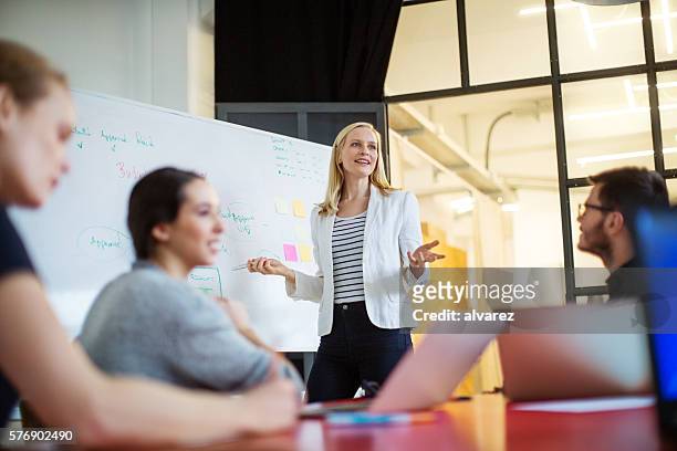 businesswoman giving presentation on future plans to colleagues - marketing stockfoto's en -beelden