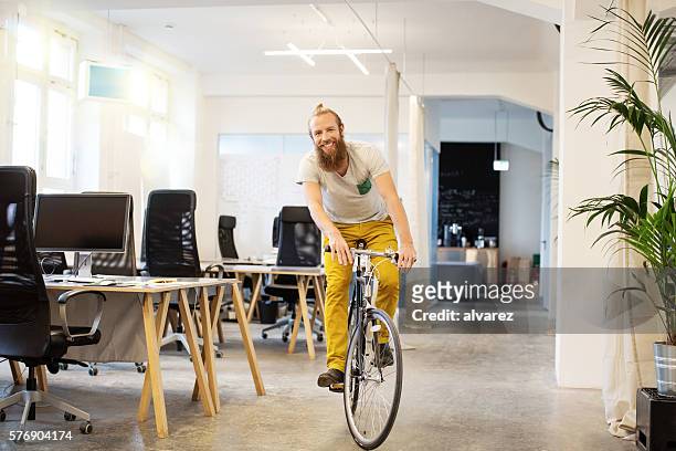 felice giovane in bicicletta in una startup - cool attitude foto e immagini stock