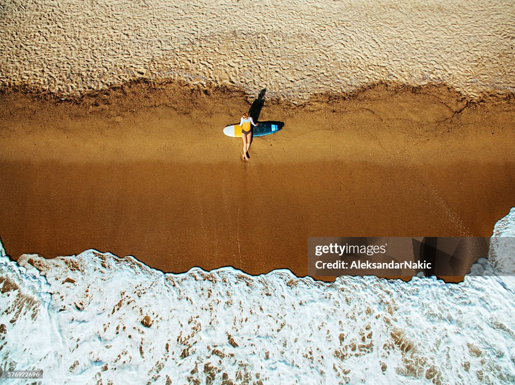 Aerial view of a surfer girl resting on a beach