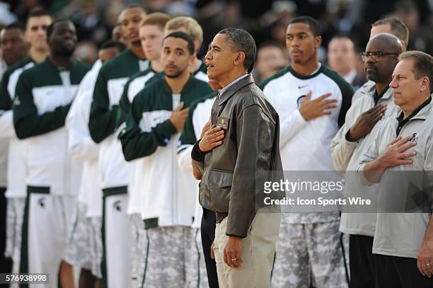 President Barack Obama stands with Michigan State during the singing of the National Anthem during the Quicken Loans Carrier Classic NCAA basketball...