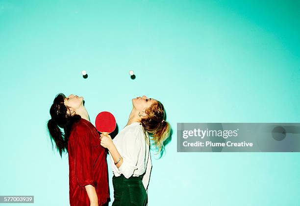 friends blowing ping-pong balls up. - sport blue background stockfoto's en -beelden