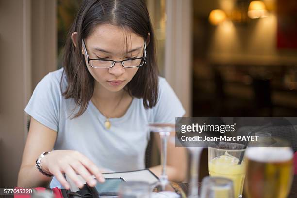 young girl with a phone in a restaurant - jean marc payet stock-fotos und bilder