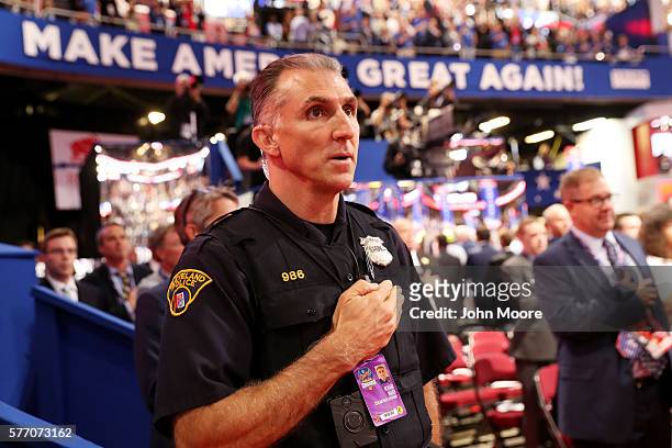Police officer and delegates sing the national anthem on the first day of the Republican National Convention on July 18, 2016 at the Quicken Loans...