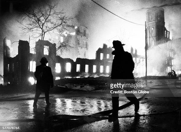 Two firefighters are silhouetted against a nine-alarm fire at Lawrence Mills in Lowell, Mass. On March 23, 1987. The fire began in a six-story...