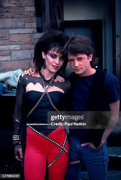 Portrait of American musician and actress Joan Jett and Canadian actor Michael J Fox as they pose outside the Thirsty Whale bar during filming of the...