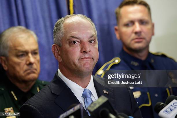Louisiana Governor John Bel Edwards speaks, center, about three local police officers who were killed by gunman Gavin Long Sunday morning during a...