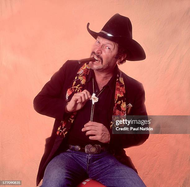 Portrait of American musician, author, and comedian Kinky Friedman as he poses backstage during the Farm Aid benefit concert at Texas Stadium,...