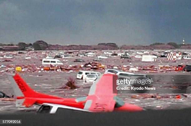 Natori, Japan - Still image taken from video footage shows a light airplane and cars being swept away by a tsunami at Sendai airport in Miyagi...