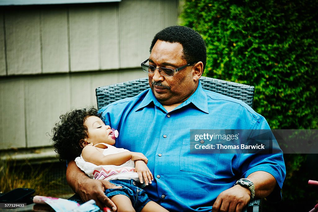 Grandfather holding sleeping toddler granddaughter