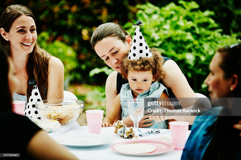 Toddler girl wearing party hat sitting with aunt