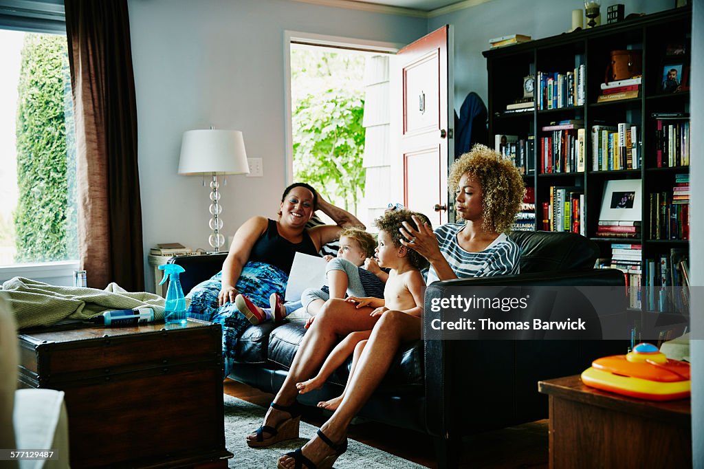 Mother combing daughters hair in living room