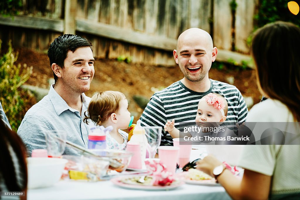 Fathers sitting at table with infant daughters