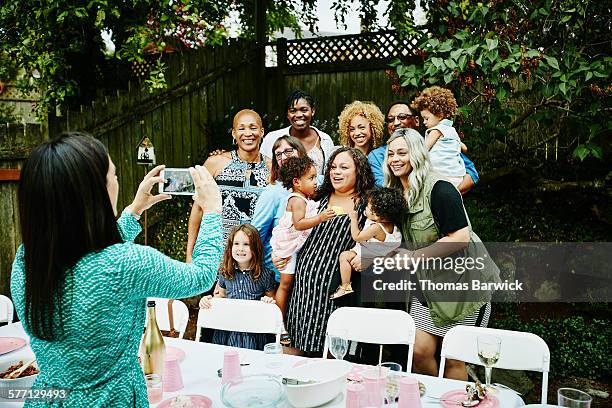 woman taking photo with smartphone of family - multigenerational multiracial group stock pictures, royalty-free photos & images