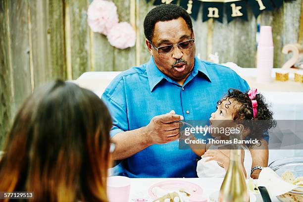 grandfather feeding granddaughter cake at party - older woman birthday stock pictures, royalty-free photos & images