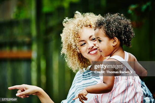 smiling woman holding toddler niece during party - contemplation family stock pictures, royalty-free photos & images