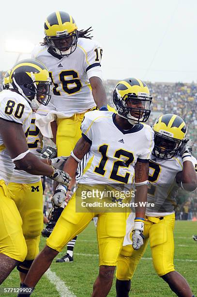 Roy Roundtree of the University of Michigan celebrates his touchdown with teammates Martell Webb , Vincent Smith and a leaping Denard Robinson during...